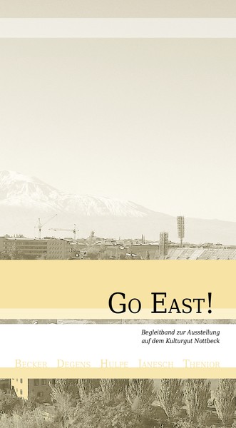 Cover des Bandes "Go East", zeigt eine Schwarzweißfotografie eines Stadions vor einer Bergkette, Armenien